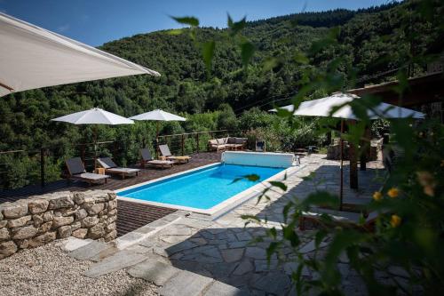 a swimming pool with chairs and umbrellas next to a mountain at d'une Source in Asperjoc