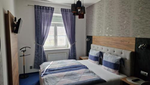 Penzion PIANO & Apartment Sokolov في سوكولوف: غرفة نوم مع سرير مع ستائر أرجوانية ونافذة
