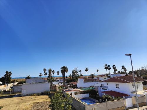 a view of a city with palm trees and houses at Arte y natura en la playa de Eucaliptus in L'Eucaliptus