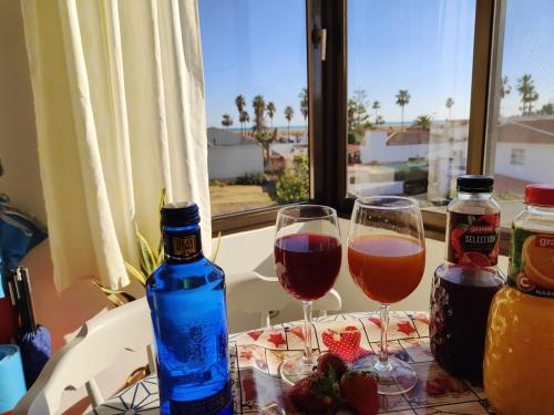 two glasses of wine and a bottle on a table at Arte y natura en la playa de Eucaliptus in L'Eucaliptus