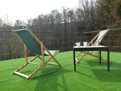 two chairs and a table on a green lawn at Dom Granero w Lesie pod Ślężą in Strzegomiany