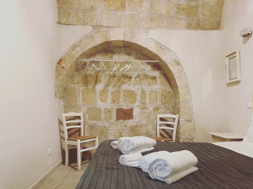 a bedroom with a stone wall with towels on a bed at Donna Nina in Monopoli