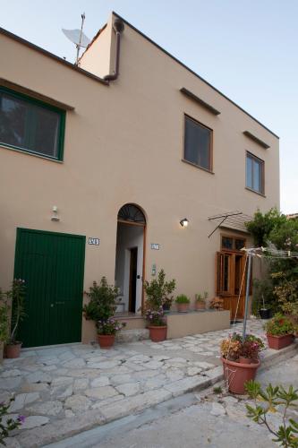 a house with a green door and some plants at Vito nel Baglio in Scopello