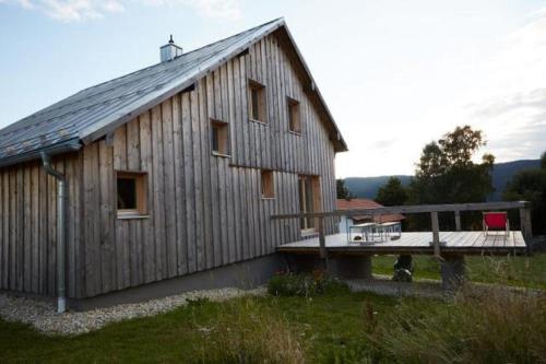 a large wooden barn with a deck and a table at Lichtzeit in Mauth