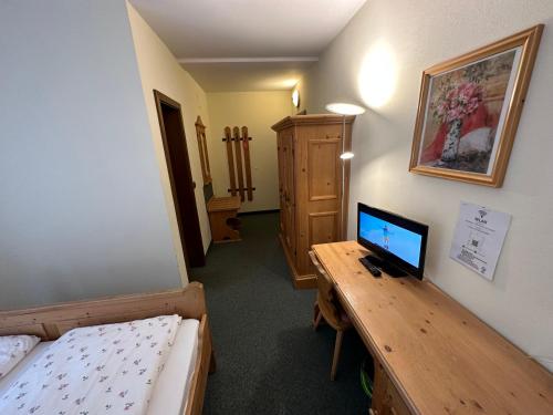 een kamer met een bed en een bureau met een computer erop bij Hotel Almenrausch in Neukirchen