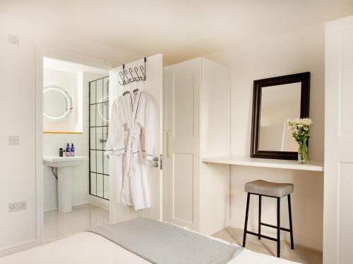 a white bathroom with a robe hanging on a door at Eugene Sands in Paignton
