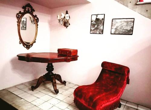 a red chair sitting next to a table and a mirror at Hotel Biscari in Catania