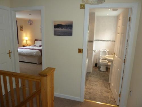 a bathroom with a toilet and a bedroom with a bed at Hendre Wen holiday cottage in Betws-y-coed