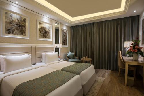 a hotel room with two beds and a desk at Singhania Sarovar Portico in Raipur