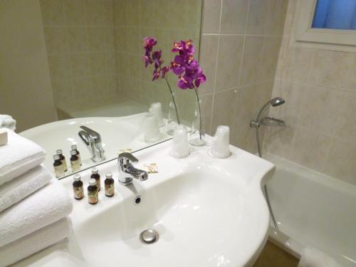 La salle de bains est pourvue d'un lavabo avec un vase de fleurs violettes. dans l'établissement Appart'City Classic Aix en Provence - Fuveau, à Fuveau