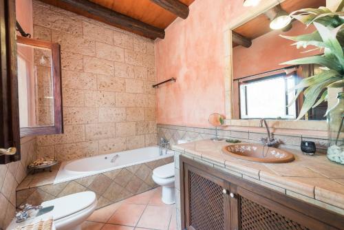 ein Badezimmer mit einem Waschbecken, einem WC und einem Spiegel in der Unterkunft Casa Angela in Capdepera