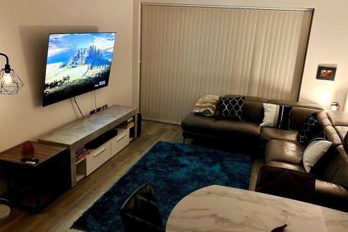 Luxury Top Floor Apartment in London في لندن: غرفة معيشة مع أريكة وتلفزيون بشاشة مسطحة
