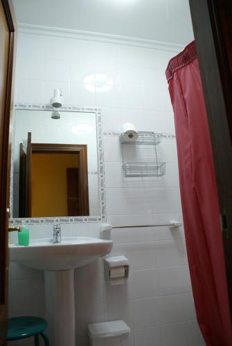 a white bathroom with a sink and a mirror at La Casa Verde del Sella in Mesariegos