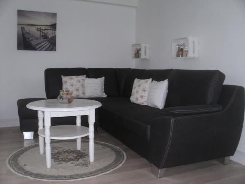 ein schwarzes Sofa mit einem weißen Tisch im Wohnzimmer in der Unterkunft House Louise. in Risum-Lindholm