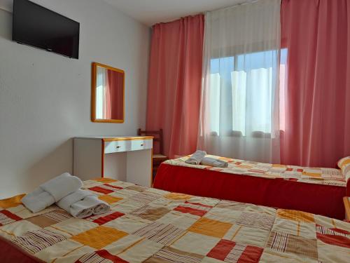 um quarto de hotel com duas camas e uma janela em Hostal Restaurante Venta del Barro em La Puebla de Híjar
