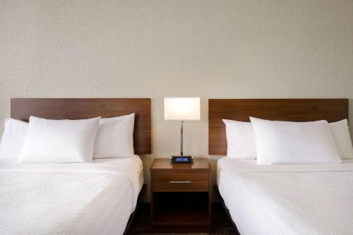 a hotel room with two beds and a lamp on a night stand at Days Inn & Suites by Wyndham Yorkton in Yorkton