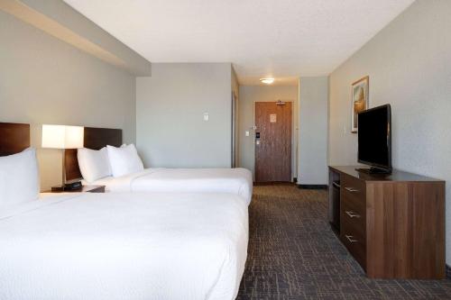 a hotel room with two beds and a flat screen tv at Days Inn & Suites by Wyndham Yorkton in Yorkton