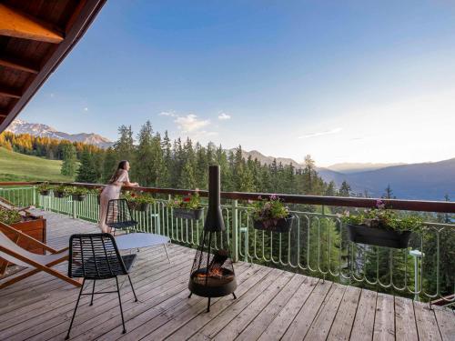 a woman standing on a deck looking at the mountains at Altezza - Arc 1800 Hotel & Spa - ex Mercure in Arc 1800