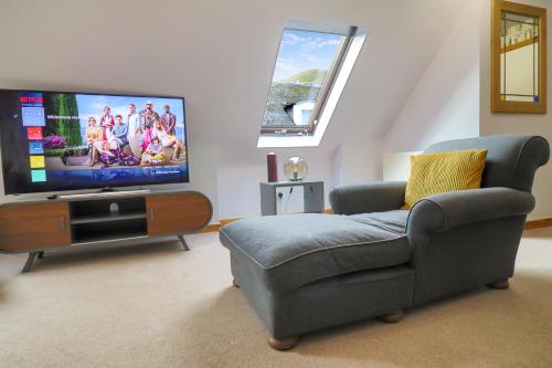 a living room with a couch and a flat screen tv at Whinstone Holiday Home in Falkland in Falkland