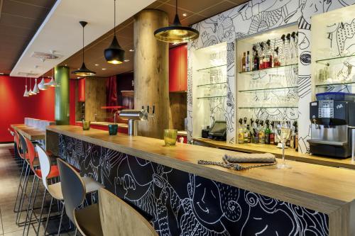 un bar con bancone in legno e sedie di Hotel Ibis Milano Ca' Granda a Milano