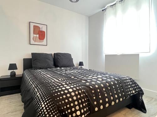 een slaapkamer met een zwart-wit bed en een raam bij Maison de ville moderne proche du centre-ville in Camon