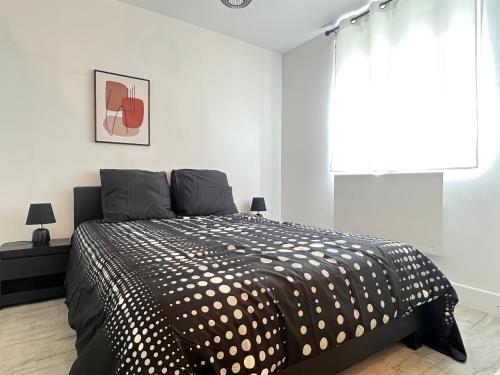 sypialnia z czarno-białym łóżkiem i oknem w obiekcie Maison de ville moderne proche du centre-ville w mieście Camon