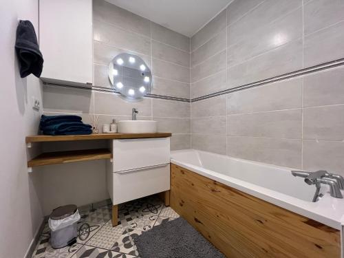 een badkamer met een bad en een wastafel bij Maison de ville moderne proche du centre-ville in Camon