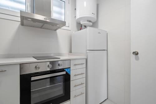 a white kitchen with a stove and a refrigerator at Formentor 863 in Salou