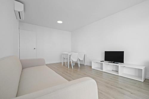 a white living room with a white couch and a tv at Formentor 863 in Salou