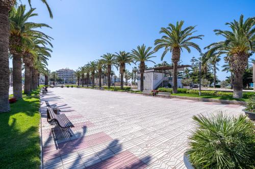 a walkway with benches and palm trees in a park at Formentor 863 in Salou