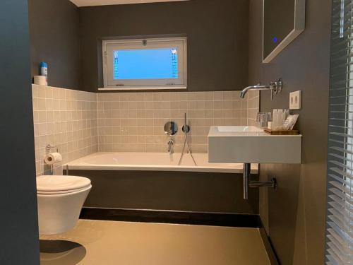 een badkamer met een bad, een toilet en een wastafel bij Bed & breakfast 23 in Amerongen