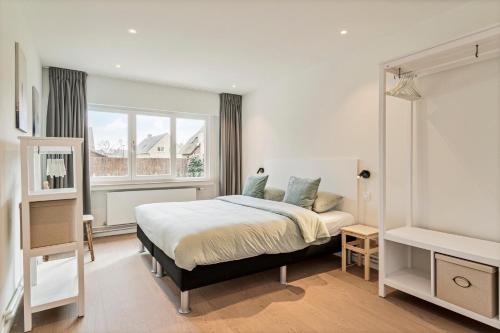 a white bedroom with a bed and a window at Maison Victor in Koksijde