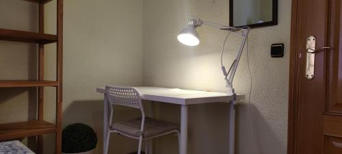 Habitación con escritorio, silla y lámpara. en Habitacion individual en apartamento céntrico, en Madrid