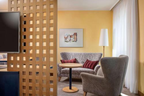 a room with a chair and a table and a tv at Vienna House by Wyndham Remarque Osnabrück in Osnabrück