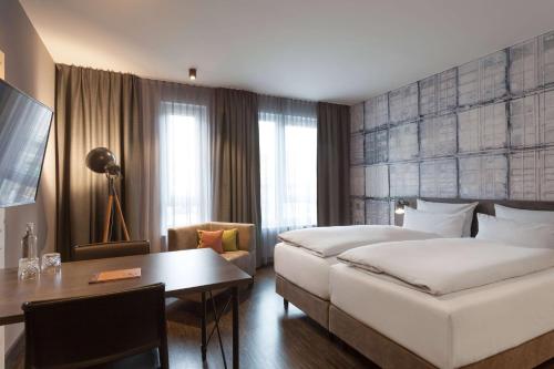 a hotel room with a bed and a desk at Vienna House Easy by Wyndham Bremen in Bremen