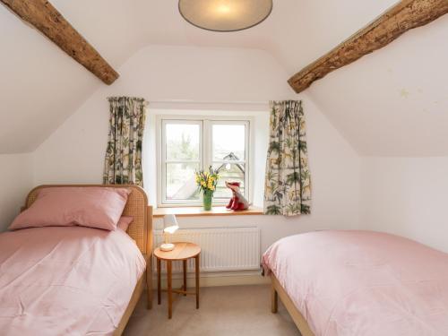 two beds in a room with a window at High Cogges Farm Holiday Cottages in Witney
