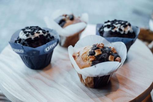 three muffins in paper cups on a wooden table at Vienna House by Wyndham MQ Kronberg in Kronberg im Taunus