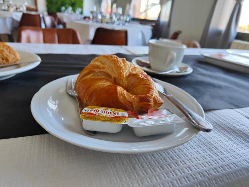 un piatto con un croissant e un contenitore di burro di Hostal Restaurante Venta del Barro a La Puebla de Híjar