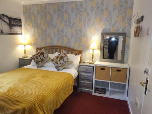 a bedroom with a bed with a yellow blanket and a tv at Maridon House in Oban