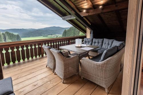 a patio with a table and chairs on a deck at Forstgut - Premium Waldchalets und Lodge Suiten in Regen