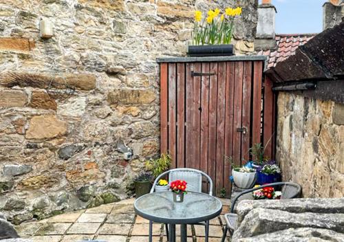 a patio with a table and two chairs and a wooden door at Whinstone Holiday Home in Falkland in Falkland