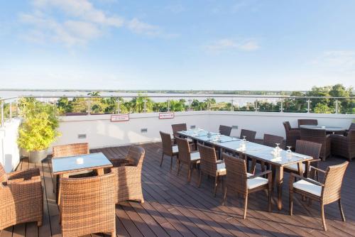 a patio with tables and chairs on a deck at Ramada by Wyndham Princess Paramaribo in Paramaribo
