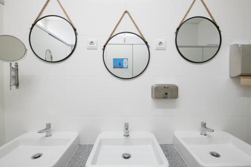 a bathroom with two sinks and two mirrors at Ínsua Hostel in São Pedro do Sul
