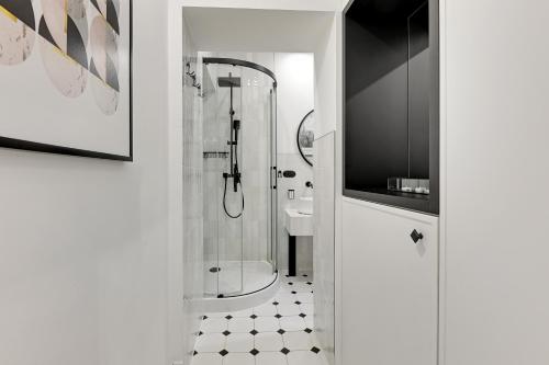 a white bathroom with a shower and a sink at Sopot Monte Cassino by Downtown Apartments in Sopot