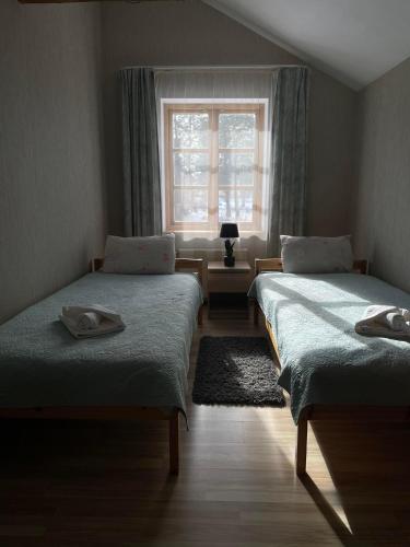 two beds in a room with a window at Spēlmaņu krogs in Alsunga