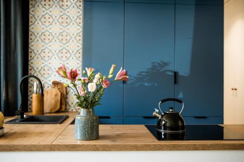 a kitchen counter with a vase of flowers and a sink at Kowalska no 4 Apartment in Gdańsk