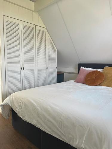 a bedroom with a large white bed and white cabinets at De hoftuin Ilpendam appartement in Ilpendam