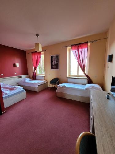 a large room with three beds and two windows at Dworek Sobieskiego in Skierniewice