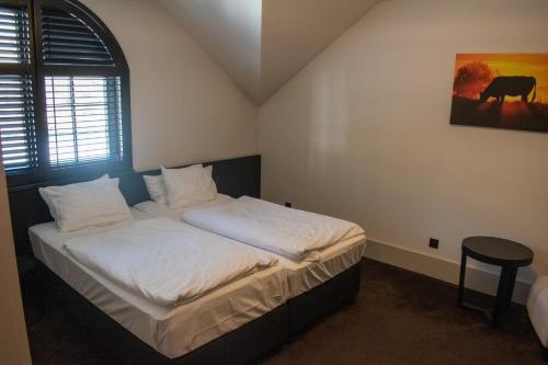 a bedroom with a bed with white sheets and a table at Hotel Pałac Jugowice in Wałbrzych