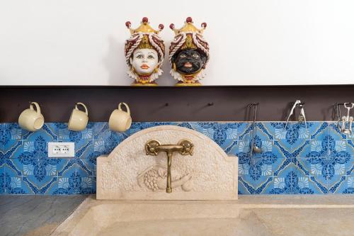 baño con lavabo y máscara en la pared en Baglio Maranzano - Don Carlo, en Buseto Palizzolo